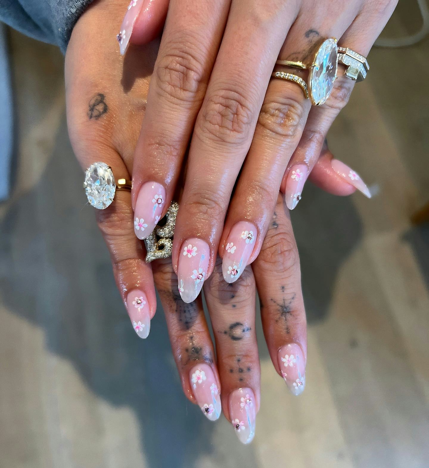 Hailey Bieber shows off cherry blossom nails and both of her engagement rings in a close-up photo.