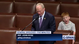 Rep. Rose delivers a speech on the floor of Congress while his son, Guy, makes silly faces behind h...
