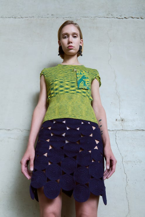 model wearing green top and black skirt