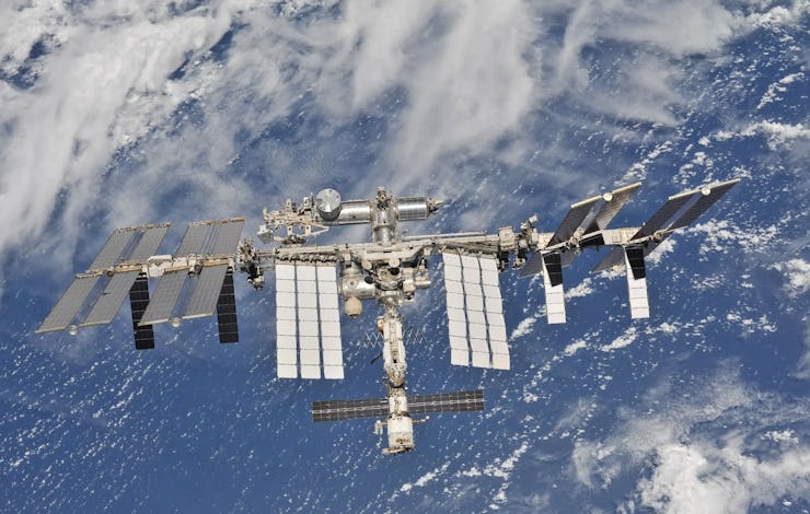 Aerial view of the International Space Station orbiting Earth, with detailed solar panels and module...
