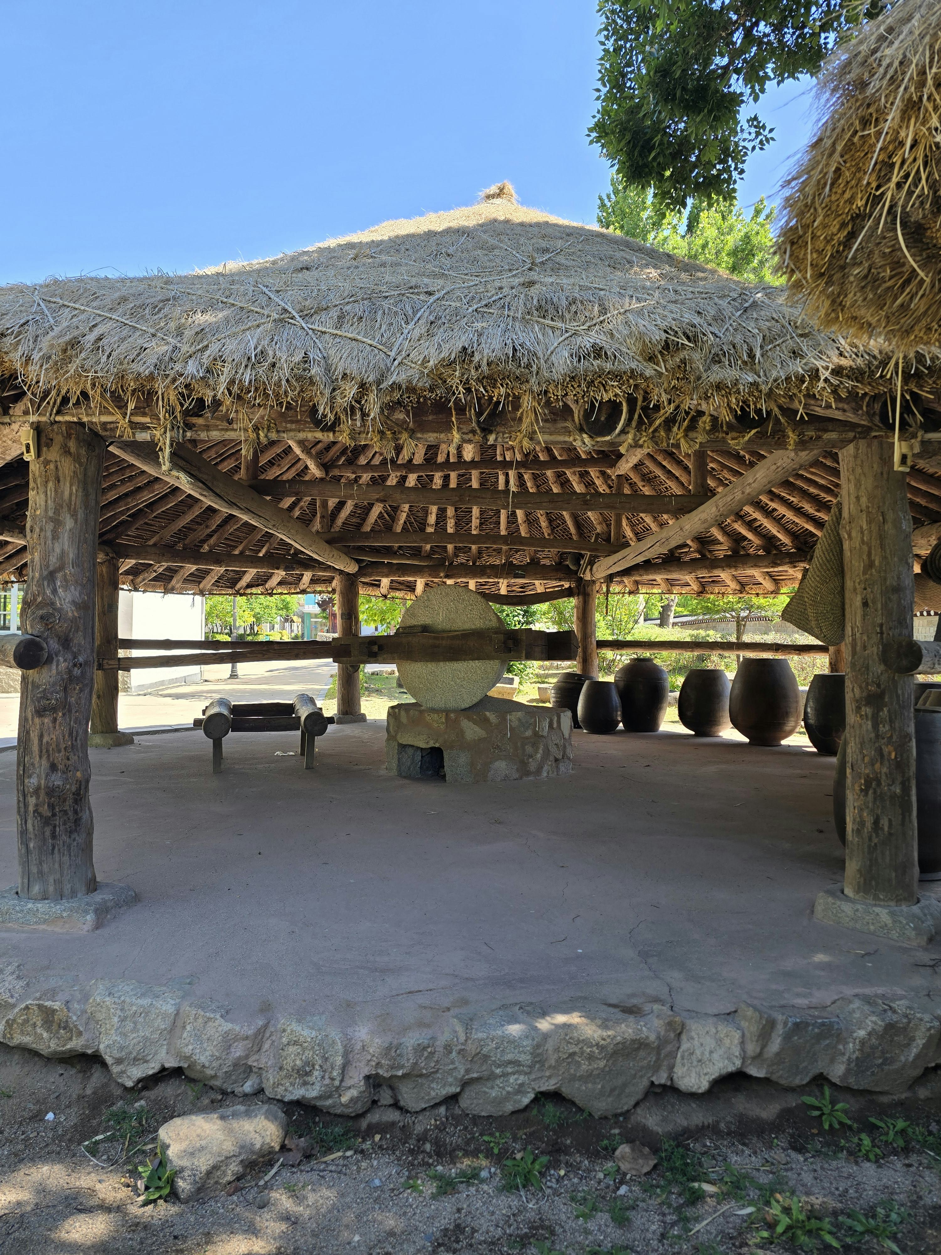 Thatched roof pavilion with traditional stone and pottery vessels displayed at Gyeongbokgung Palace&hellip;.