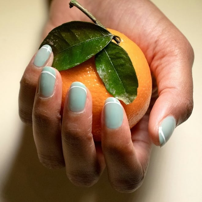 jinsoon hand model with pastel green and white french mani with orange in hand
