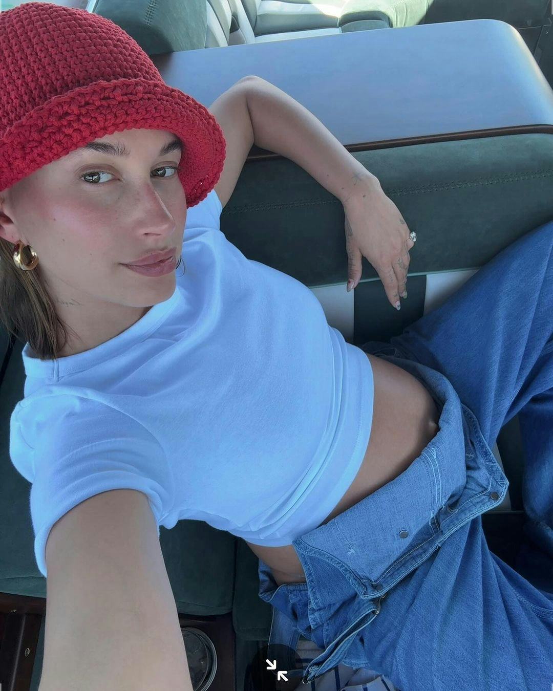 Hailey Bieber wears a white crop top and overalls.
