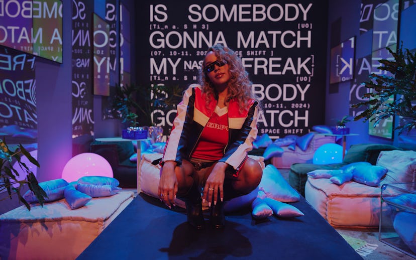A stylish young woman poses confidently in a vibrant room with neon lights and graffiti-like text on...