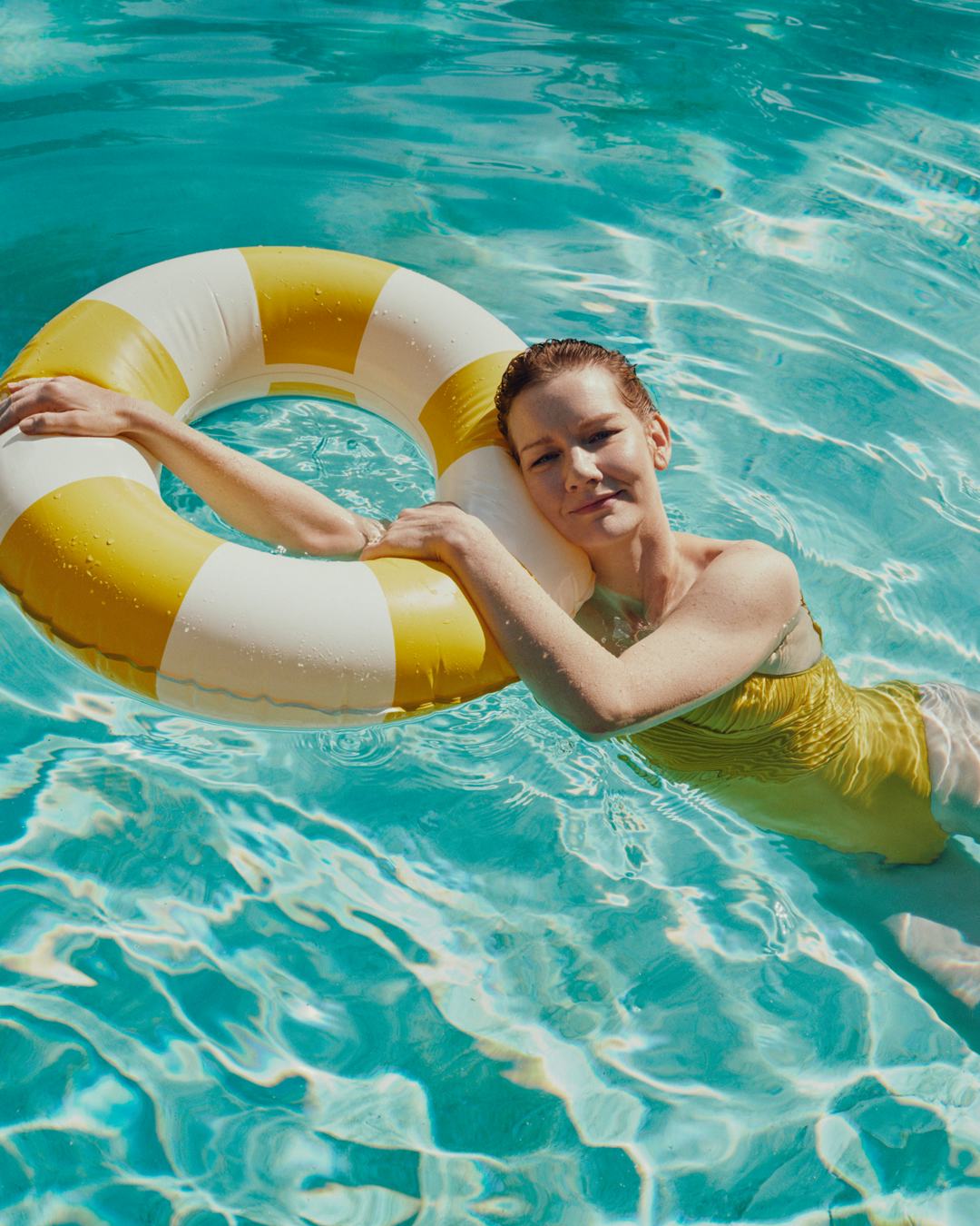 justine triet in a pool holding onto a yellow and white floatie