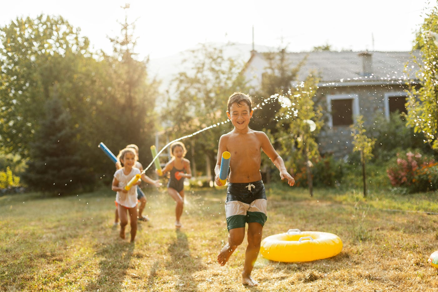 Children playing with water guns in a grassy yard, in a story answering the question, are mosquito stickers safe for kids?