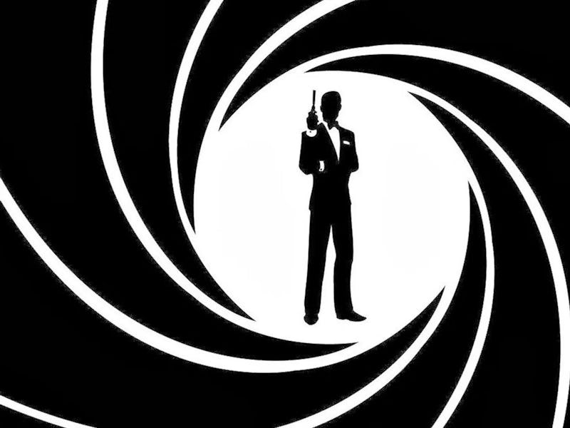 James Bond stands in the sights of a gun barrell.