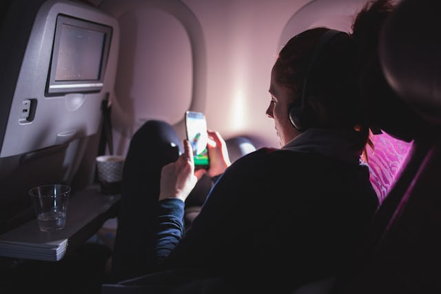 A woman watches a movie on her phone in a plane.