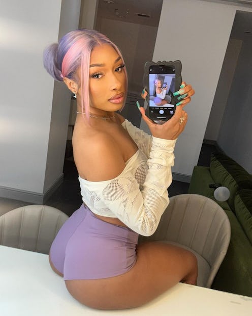 Megan Thee Stallion wears a sheer crop top and purple booty shorts.  