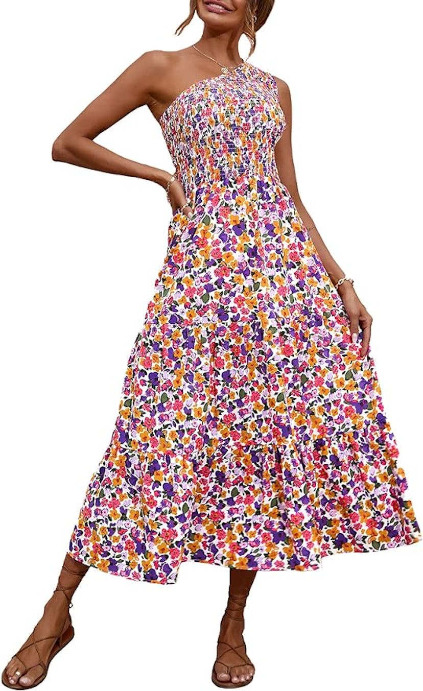 Woman in a colorful, floral-printed, strapless midi dress with tiered skirt, posing elegantly.