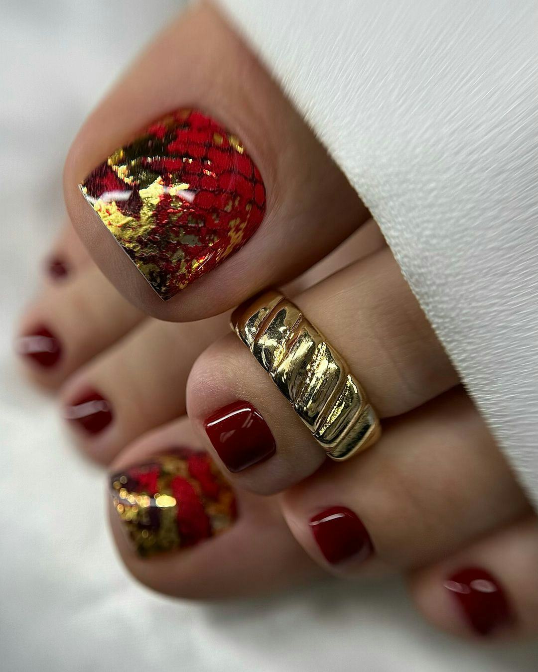 Gold leaf-covered red pedicures are perfect for Leo season 2024.