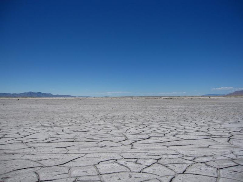 Dried lake bed of Great Salt Lake in Utah. Cracks cover the landscape. A cloudless sky looms above.