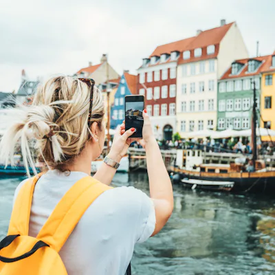 A woman takes a photo while traveling in Copenhagen.