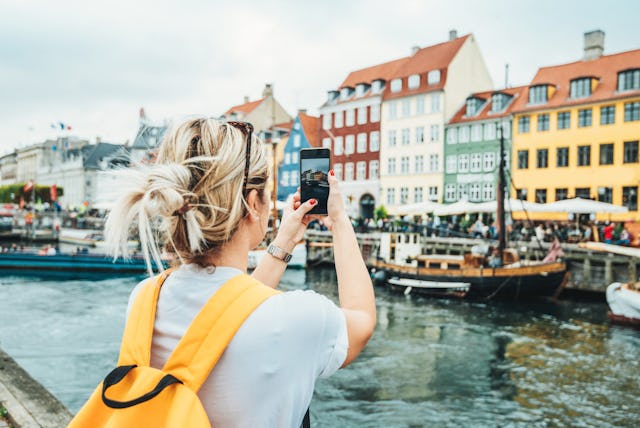A woman takes a photo while traveling in Copenhagen.
