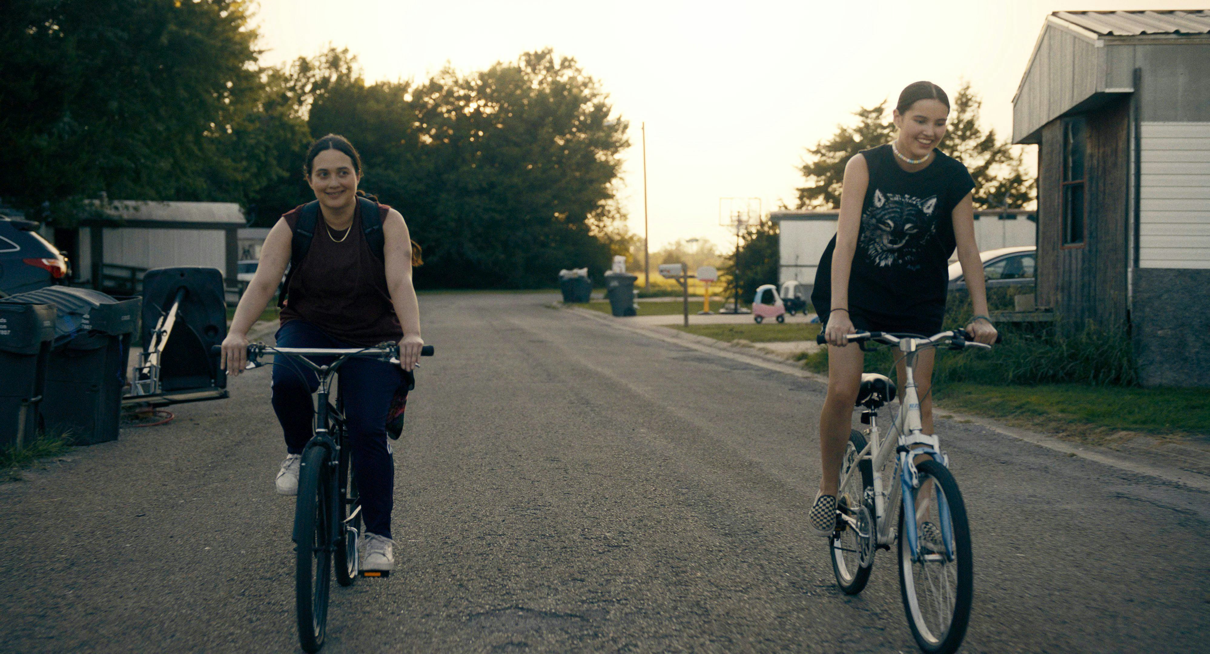 A still from Fancy Dance. The two protagonists ride bikes down the street