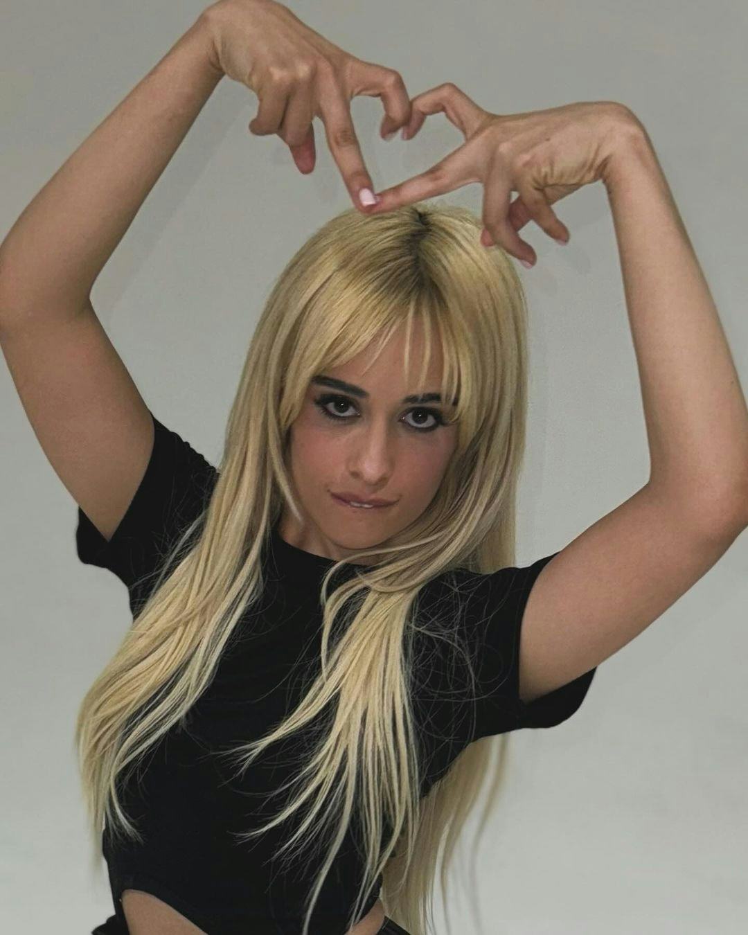 Camila Cabello wears a black dress with cutouts and ballet flats.