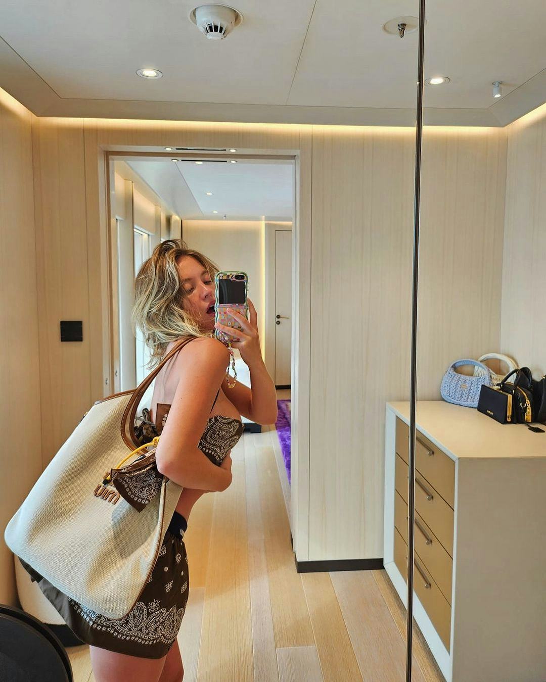 Sydney Sweeney wears a paisley print scarf as a bra, a micro mini skirt, and a canvas tote bag.