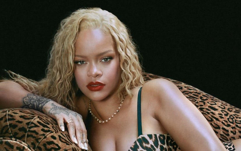 A woman with blonde hair in a leopard print outfit lounges on a matching sofa, looking directly at t...