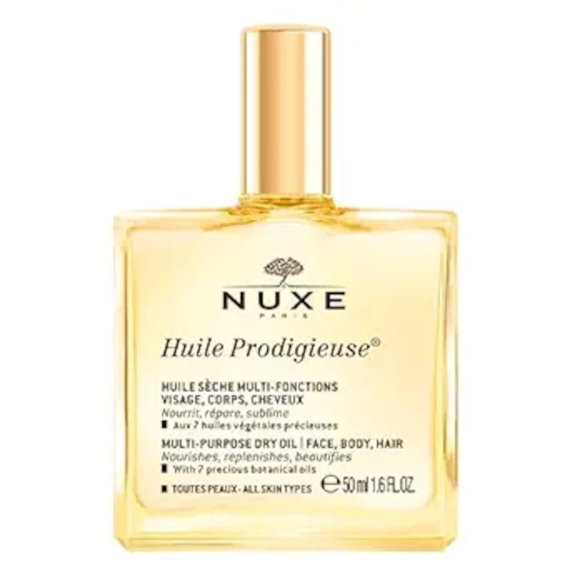 A clear glass bottle of NUXE Huile Prodigieuse, a multi-purpose dry oil for face, body, and hair, wi...