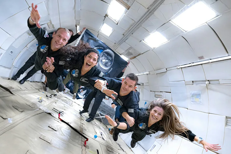 photo of 4 people in flightsuits floating inside an aircraft fuselage