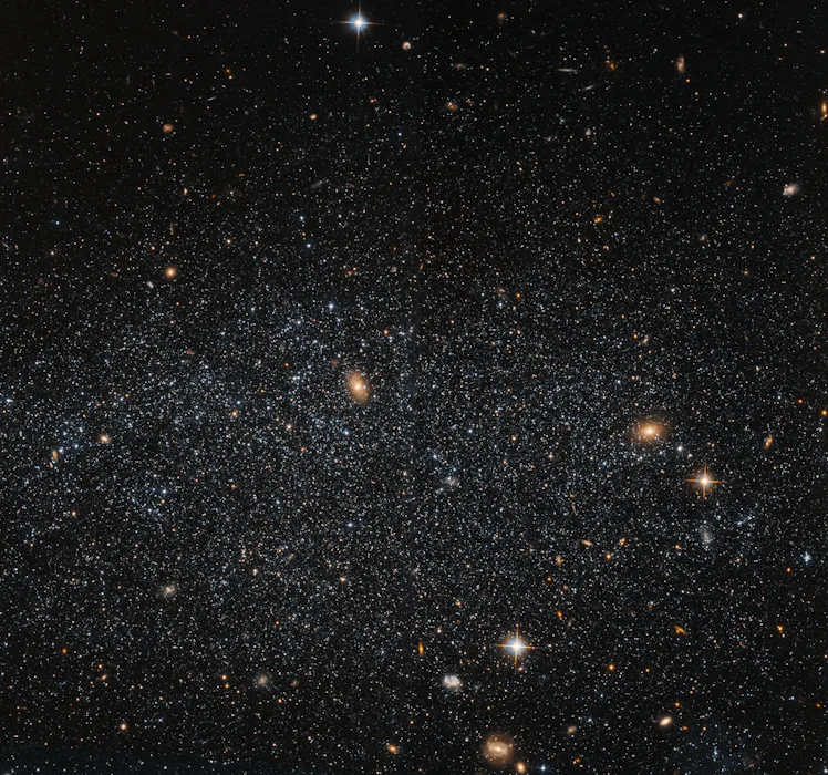 Stars are sprinkled across space. They're gathered loosely, and form a spherical shape. The gaps bet...