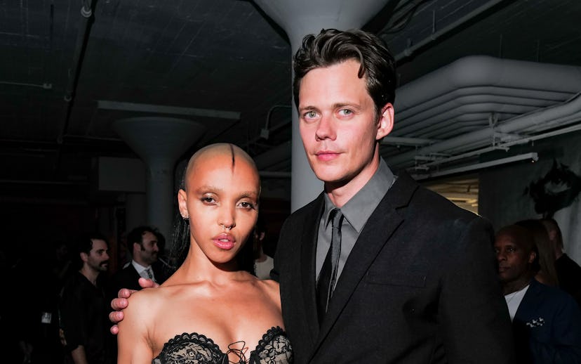 A stylish couple poses together at an event. The woman wears an elegant, sheer black dress, while th...