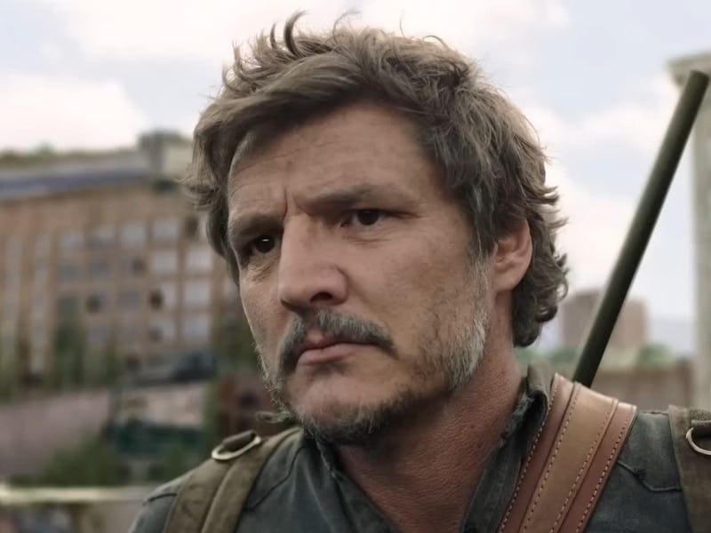 A middle-aged man with tousled hair and a mustache looks seriously at the camera, wearing a military...