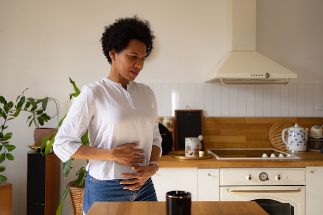 A woman holds her abdomen as she experiences period cramps.