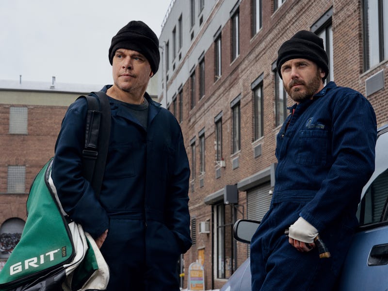 Two men in work attire, one with a sports bag, stand near a car in an urban setting, both wearing be...