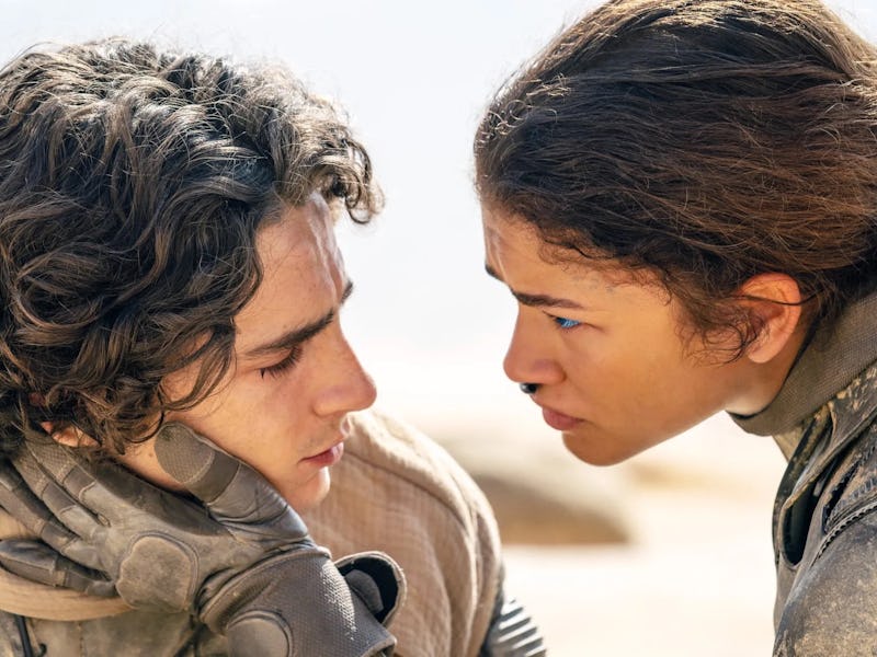 A close-up of two characters in a tense moment, gazing intently at each other amidst a desert backdr...