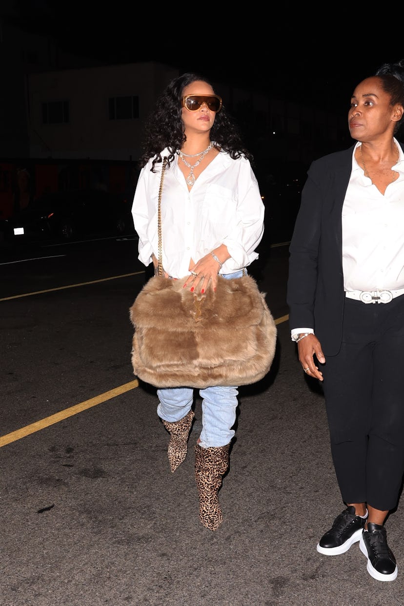 Rihanna wears a white button-up, jeans, and a massive shearling bag. 