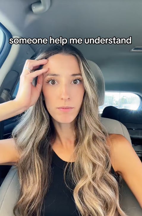 A woman with long, wavy hair sits in a car, looking confused while raising a hand to her forehead. Text above her reads, 