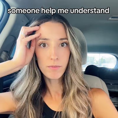 A woman with long, wavy hair sits in a car, looking confused while raising a hand to her forehead. Text above her reads,