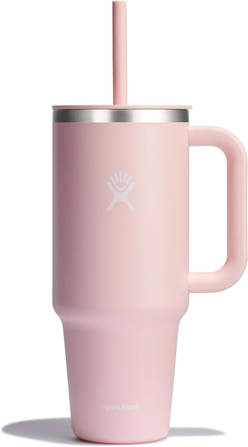 A pink Hydro Flask tumbler with a straw and a handle, featuring a stainless steel rim. It's designed...