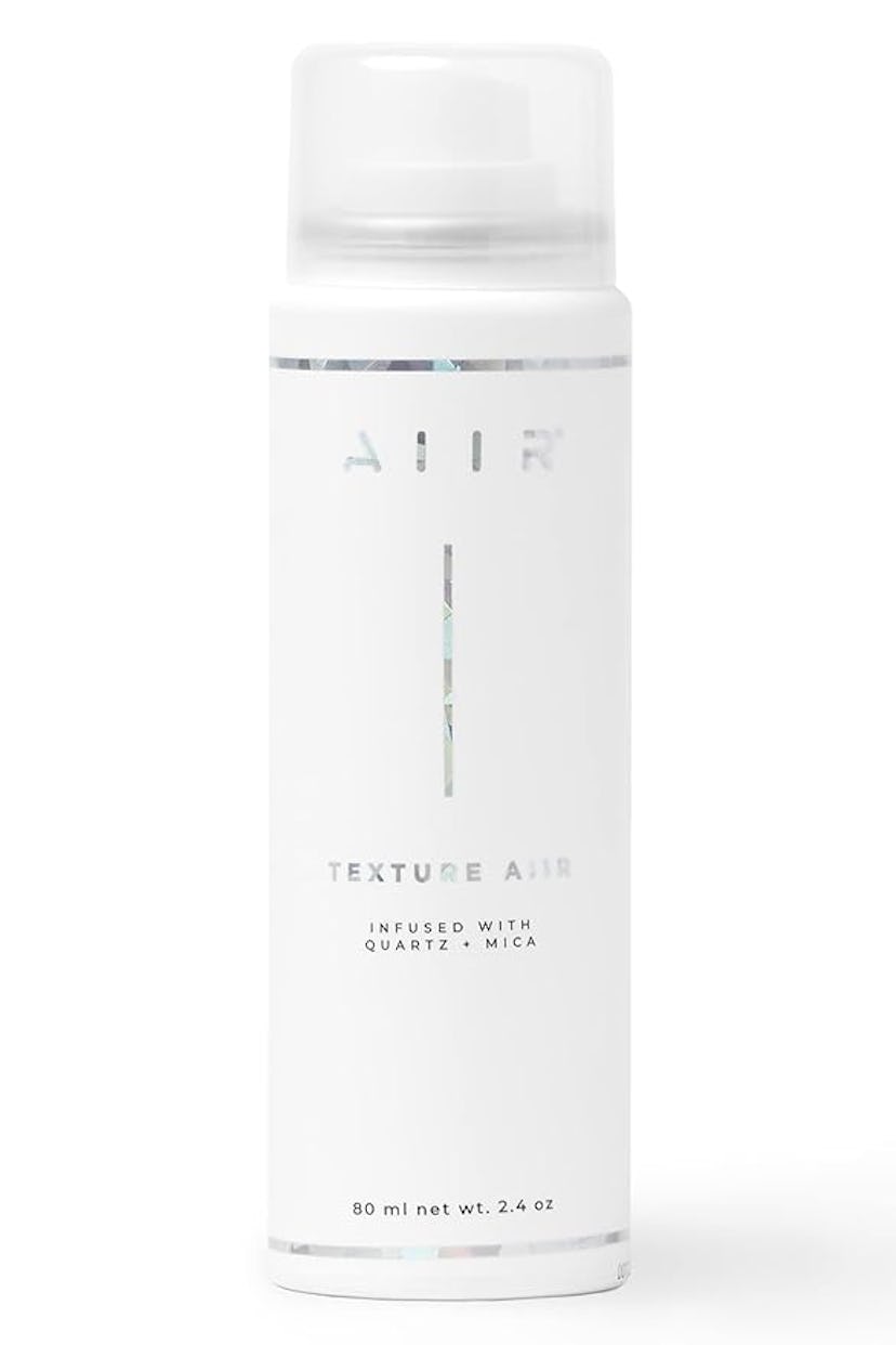 A sleek, white aerosol can labeled "AIR" with the text "TEXTURE AIR" and "INFUSED WITH QUARTZ - MICA...