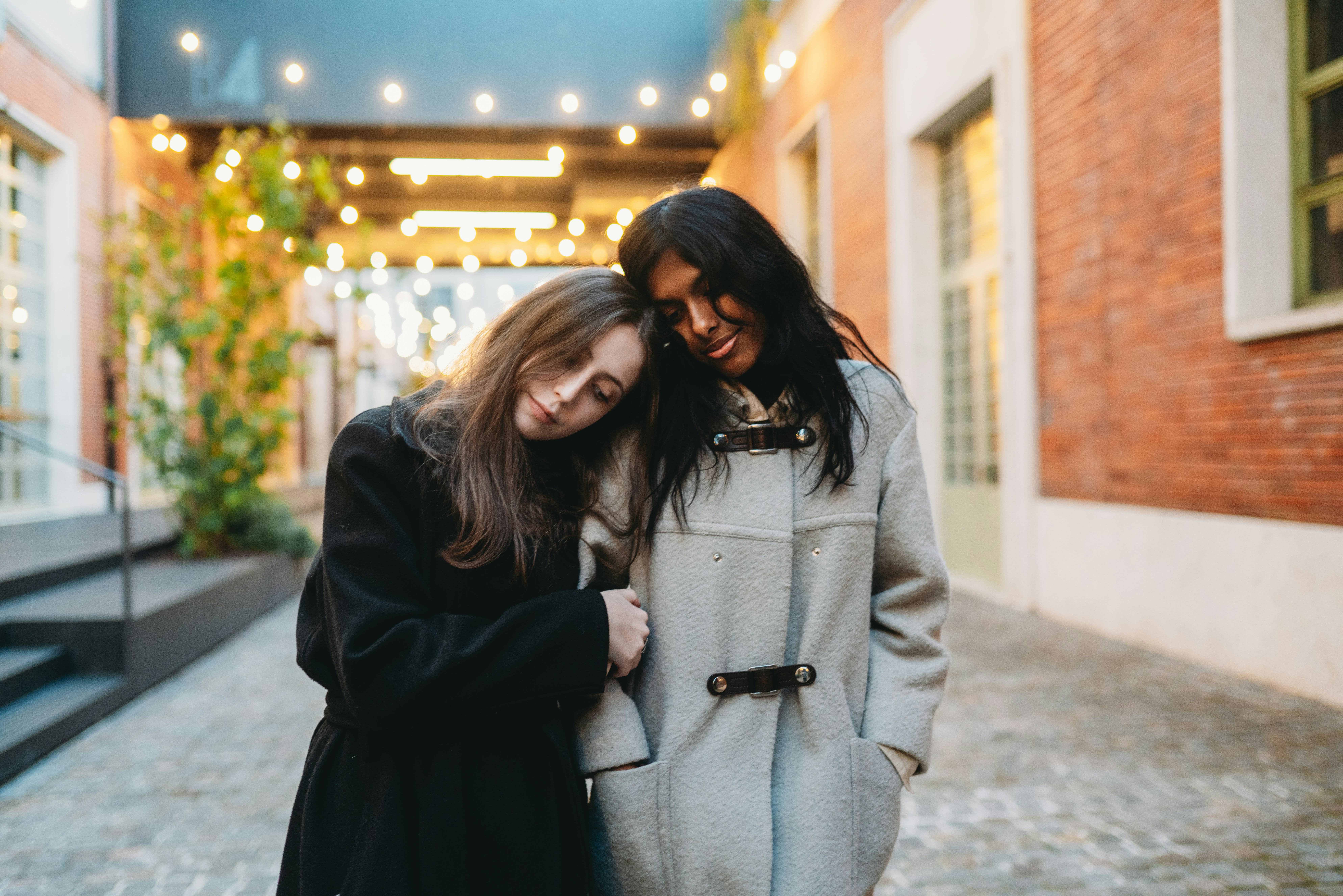Two young friends linking arms outside after reading their October 2024 horoscope.