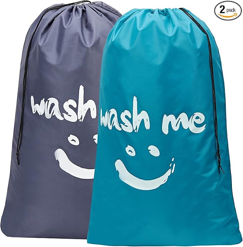 A pack of two laundry bags: one teal and one gray, both featuring the phrase "wash me" printed in wh...