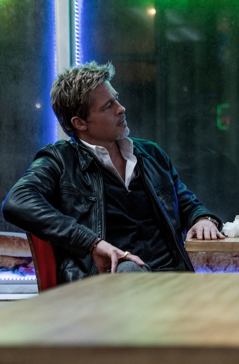 Two men sit across from each other at a table in a dimly lit restaurant, engaged in a serious conver...