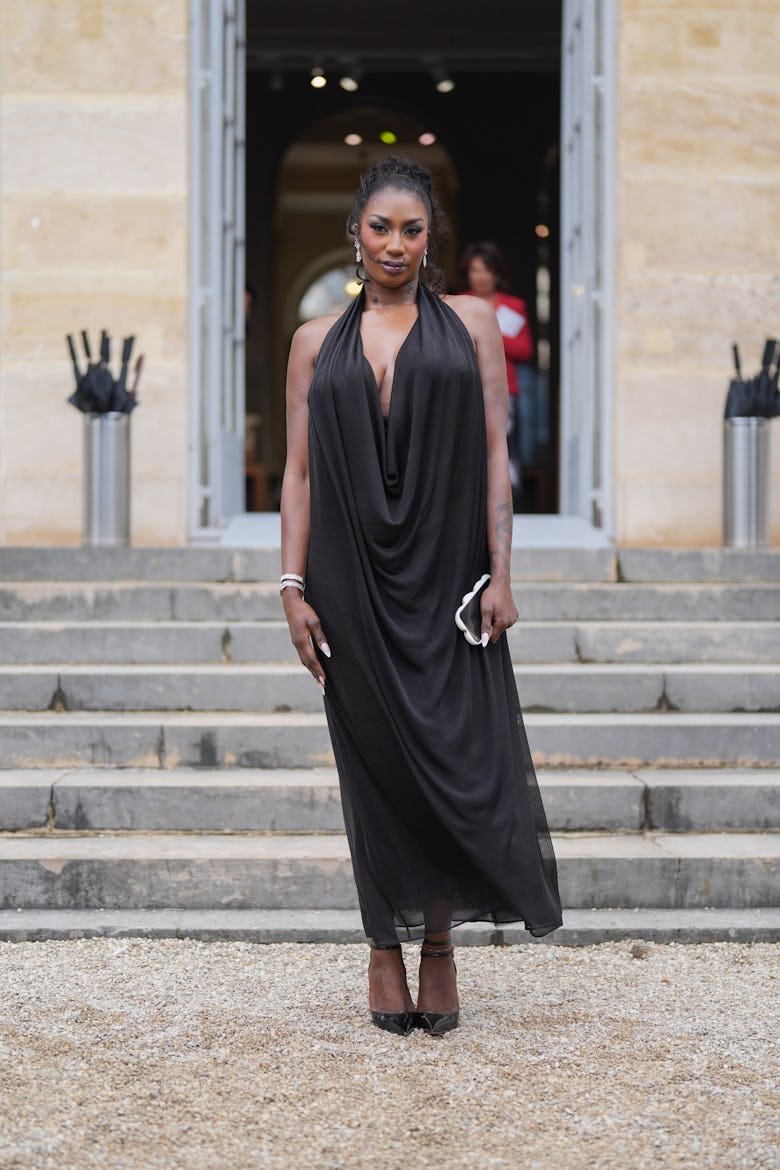 PARIS, FRANCE - SEPTEMBER 24: Aya Nakamura wears white earrings, black draped halter sheer mesh midi...
