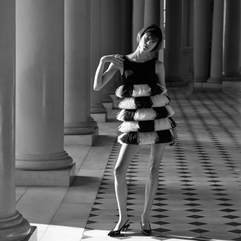 A black and white photo of a model wearing a 60s-esque dress
