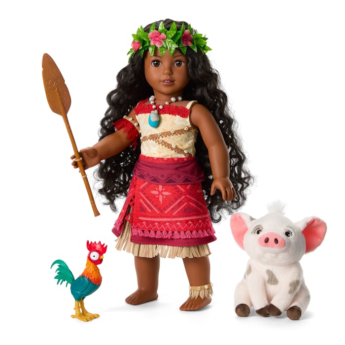 A doll with long, curly hair wearing a traditional outfit holds a spear. Beside her are a colorful r...