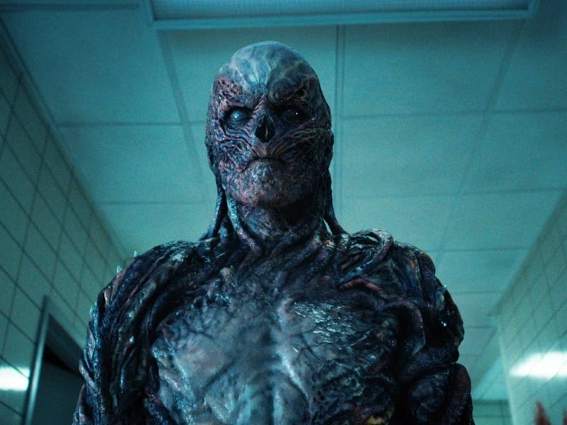 A menacing creature stands in a dimly lit hallway, featuring grotesque, textured skin and an eerie e...