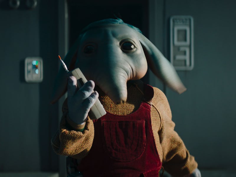 A whimsical character with an elephant-like head holds a communication device, wearing a cozy sweate...