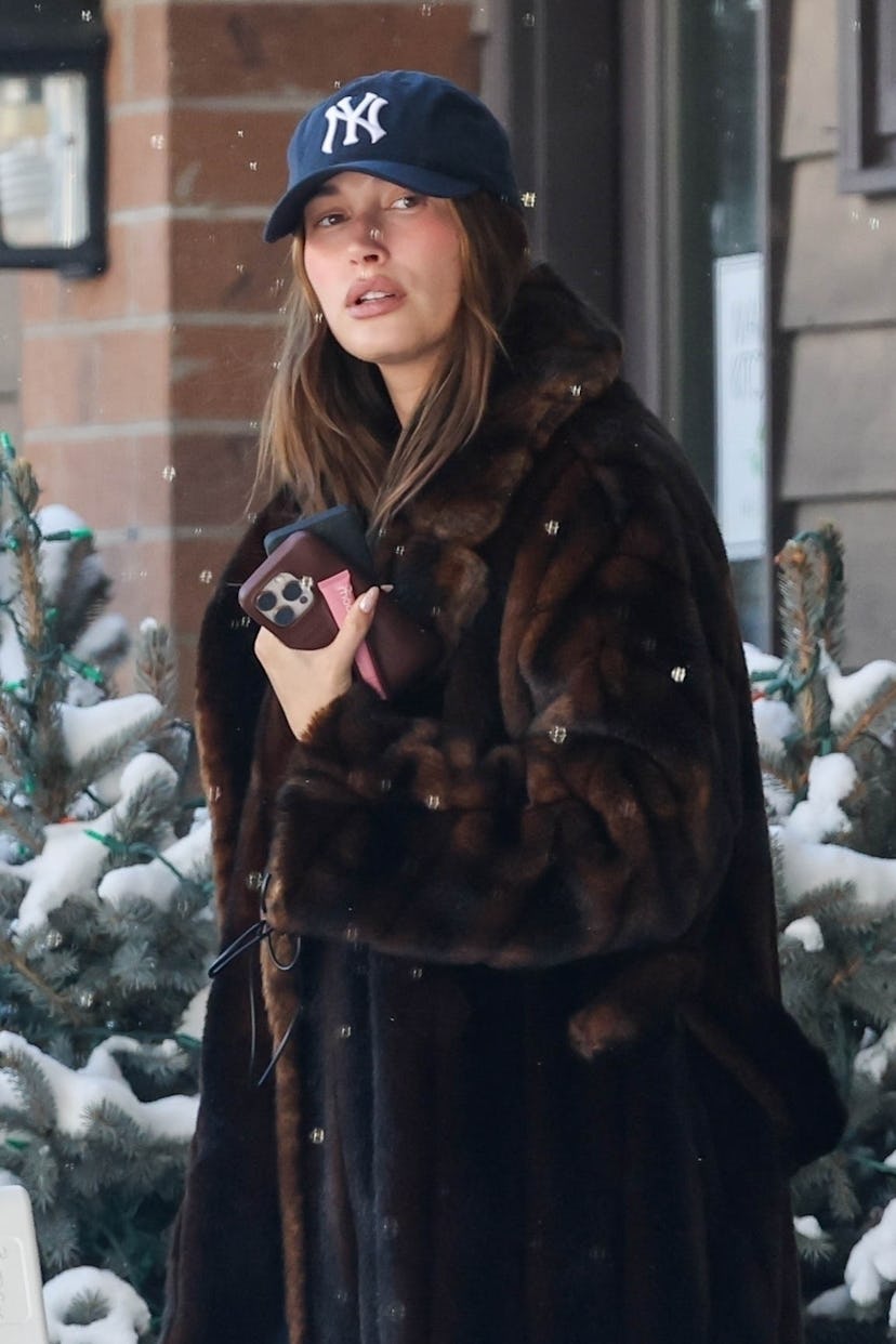 Hailey Bieber wearing a fur coat and baseball cap