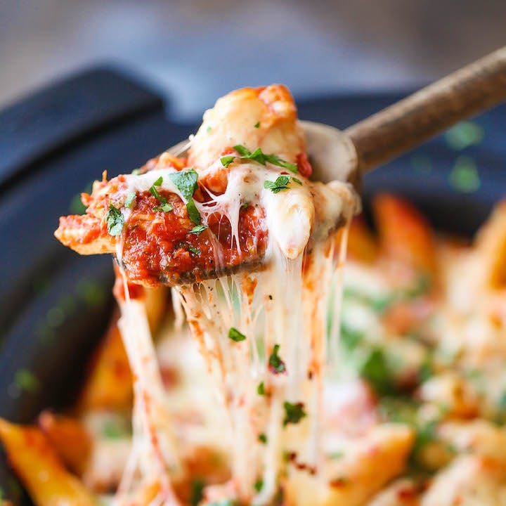 Chicken parmesan pasta, a crockpot chicken recipe, being spooned out of the crockpot.