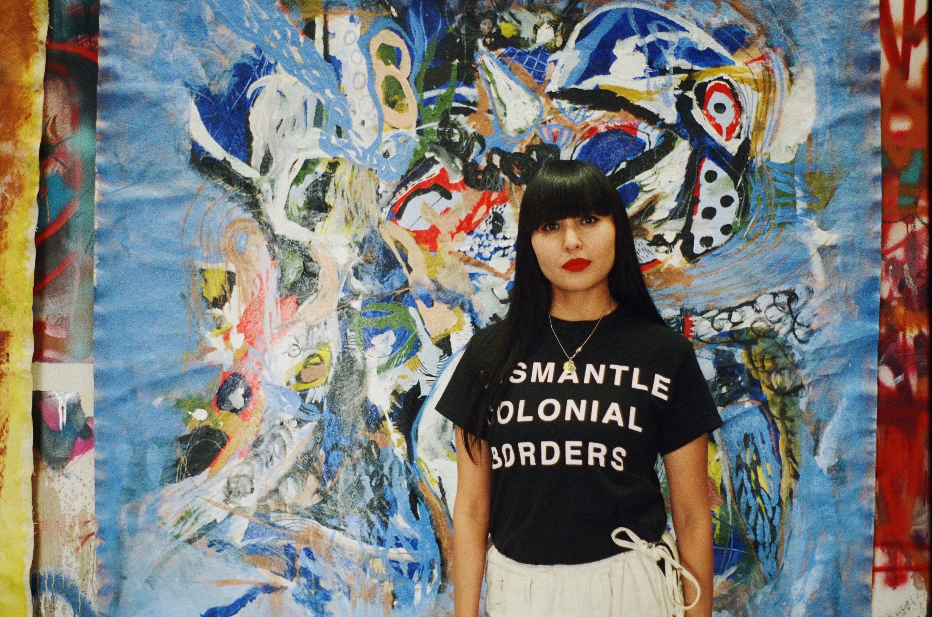 Nizhonniya Austin standing in front of one of her paintings