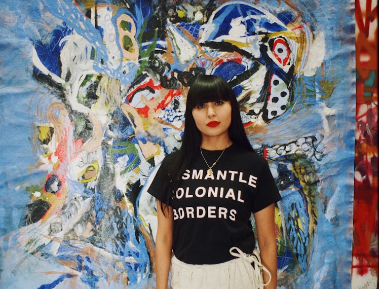 Nizhonniya Austin standing in front of one of her paintings