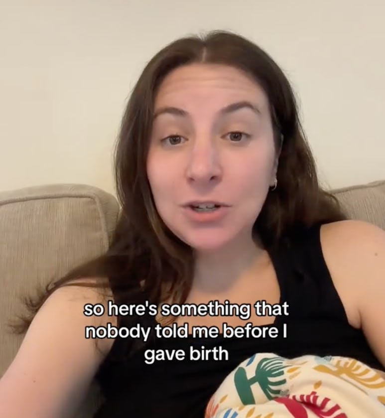 A woman with long hair sits on a couch, speaking directly to the camera. She shares insights about childbirth, expressing surprise at what she learned.
