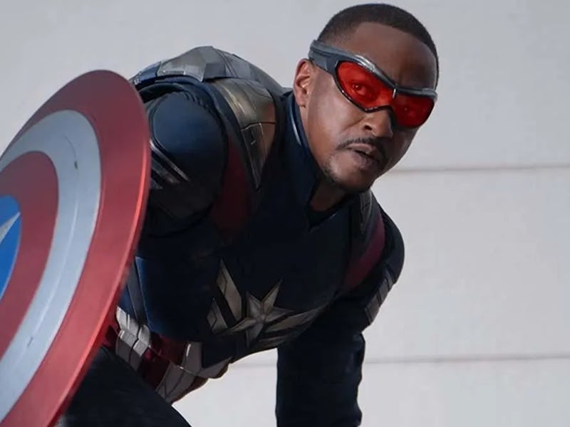 A superhero in a dark blue costume with a star emblem, red goggles, and a shield, poised heroically ...