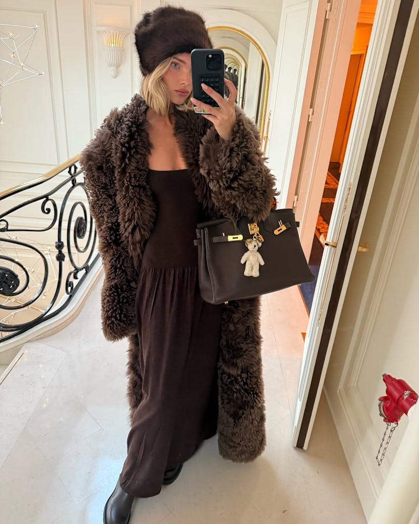 Elsa Hosk wears a brown dress, shaggy jacket, and an Hermès Birkin.